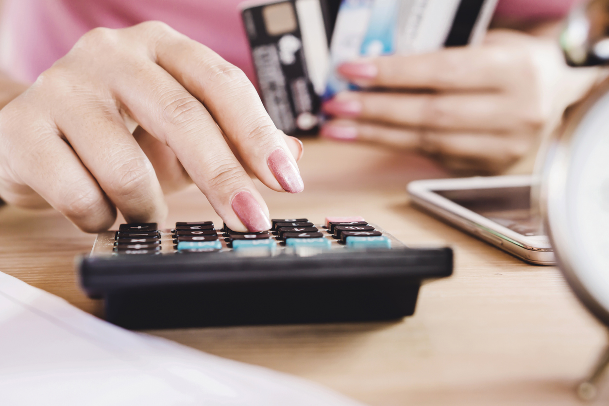 Deeming Rates woman hand calculating her expenses and debt from credit cards