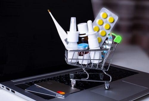 Commonwealth Seniors Health Card On the laptop is a shopping cart with medicines and credit cards. Online shopping. Medical concept. Pharmacology. Copy space